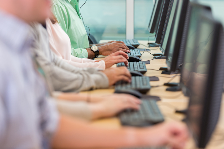 Row of diverse people typing on keyboards while working in a call center.