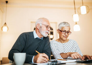 Mature couple doing some paperwork and calculations at home; Shutterstock ID 1012340377; Purchase Order: 20076173